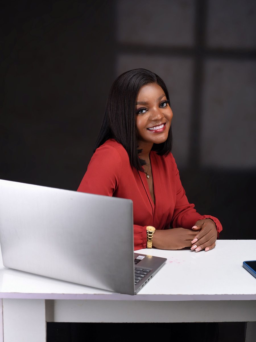 A smiling school administrator in a red blouse at her laptop