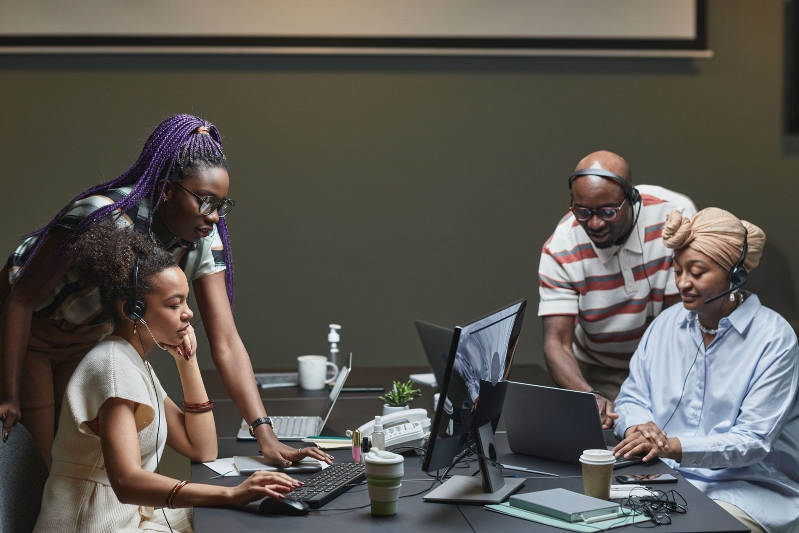 Two trainers standing beside a client's staff at their computers, walking them through the system.